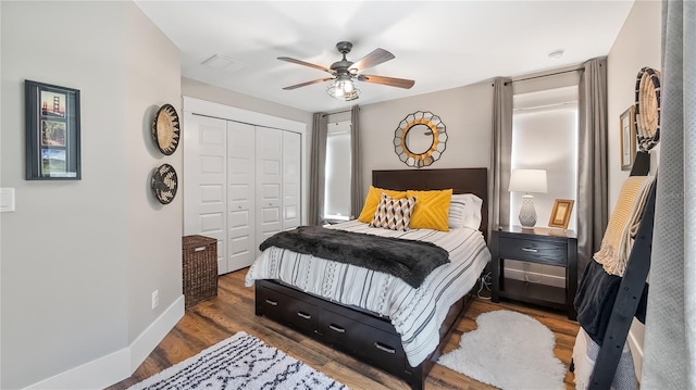 bedroom featuring wood finished floors, visible vents, a ceiling fan, baseboards, and a closet