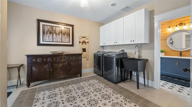 clothes washing area featuring washing machine and dryer, a sink, visible vents, cabinet space, and tile patterned floors