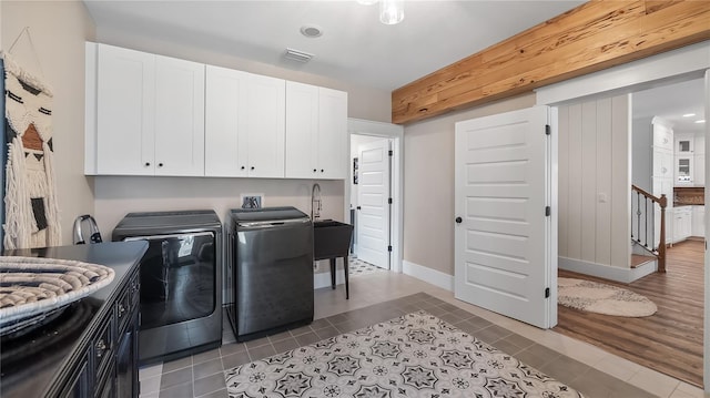 laundry room featuring cabinet space, visible vents, tile patterned flooring, separate washer and dryer, and a sink