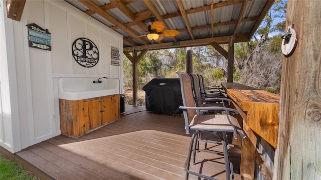 wooden terrace with a sink, grilling area, and ceiling fan