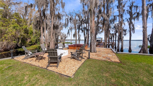 view of yard with a patio area, a dock, a water view, and a hot tub