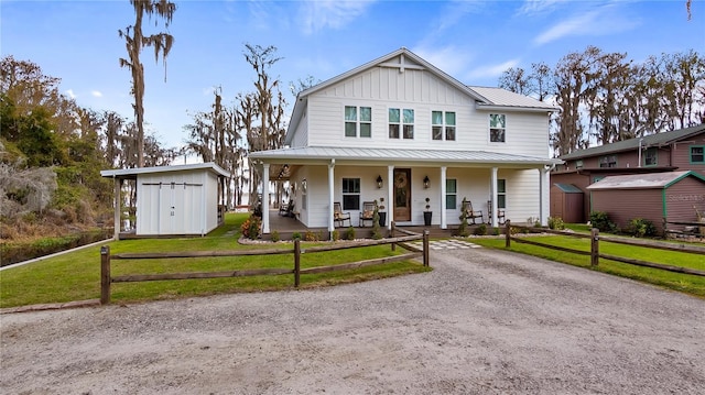 view of front of property with an outbuilding, covered porch, a storage shed, metal roof, and a front lawn