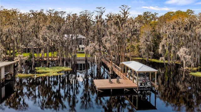 view of dock featuring a water view, boat lift, and a view of trees