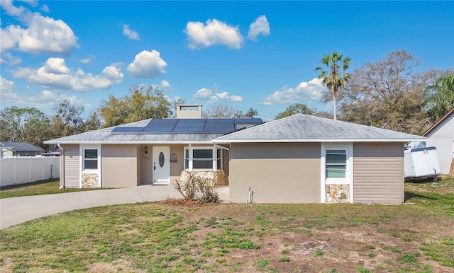 ranch-style home with solar panels, a front yard, fence, and stucco siding