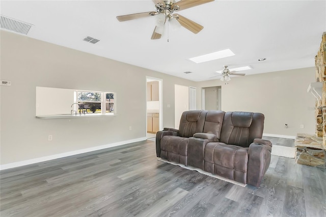 living area featuring visible vents, a skylight, and wood finished floors