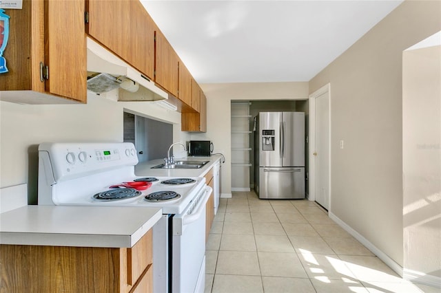 kitchen with white range with electric cooktop, brown cabinets, light tile patterned flooring, stainless steel fridge, and a sink