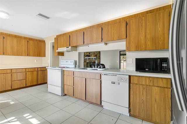 kitchen with white appliances, light countertops, under cabinet range hood, and a sink