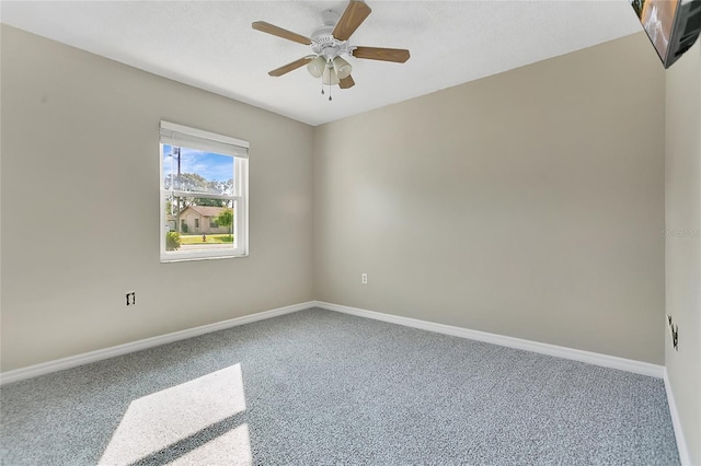 carpeted spare room featuring baseboards and ceiling fan