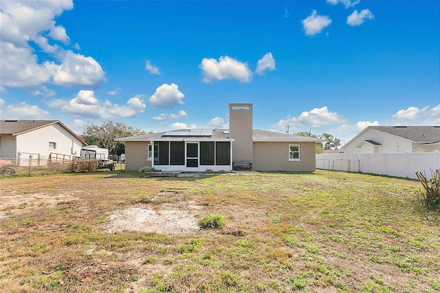 back of property with a lawn, a chimney, a fenced backyard, and a sunroom