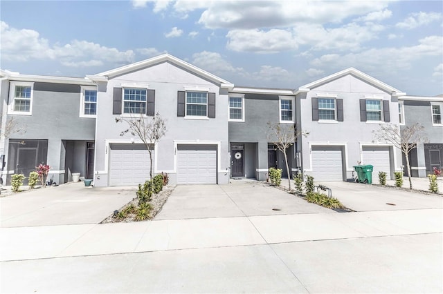 multi unit property featuring an attached garage, driveway, and stucco siding