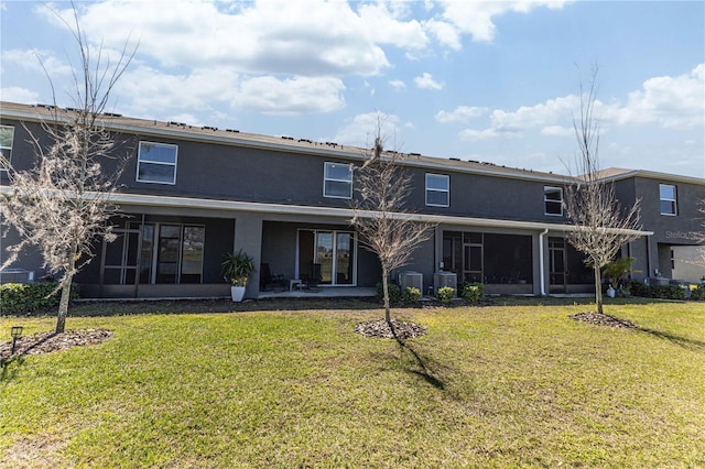 rear view of house with a sunroom, a lawn, and stucco siding