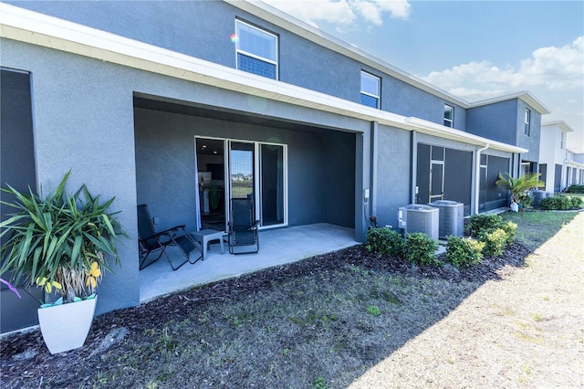 back of property with a patio area, cooling unit, and stucco siding