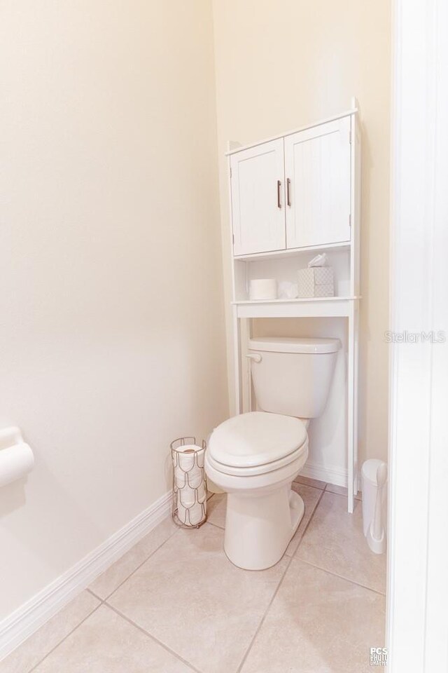 bathroom featuring tile patterned flooring, toilet, and baseboards