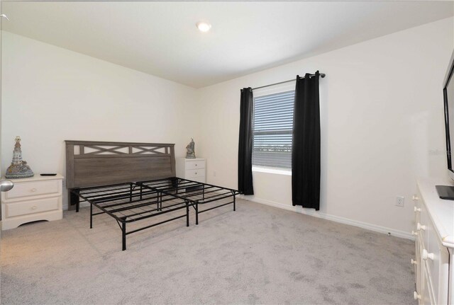 bedroom featuring light carpet and baseboards