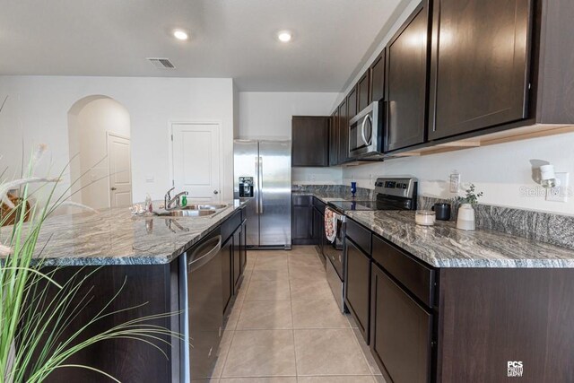 kitchen featuring stainless steel appliances, stone counters, visible vents, and dark brown cabinetry