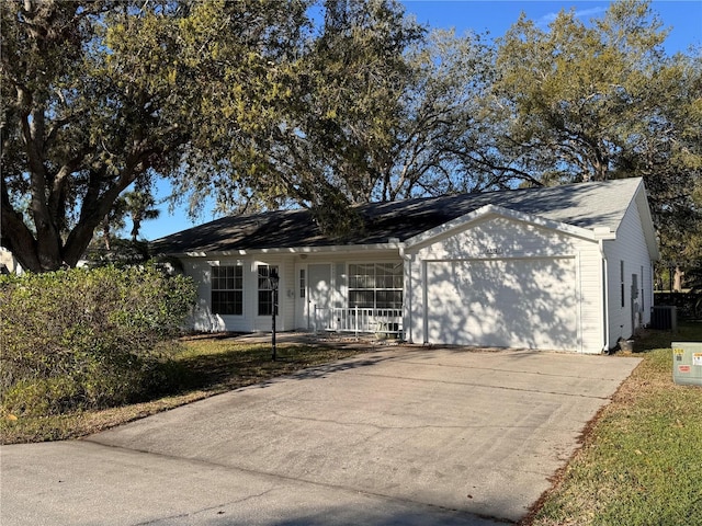 ranch-style house with concrete driveway, central AC unit, a porch, and an attached garage