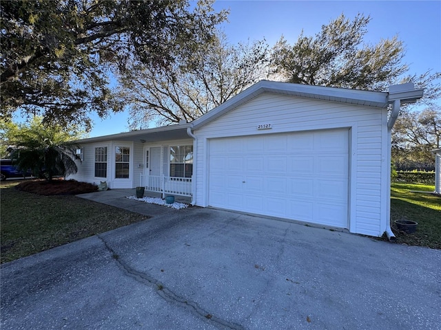 single story home featuring a front lawn, covered porch, driveway, and an attached garage