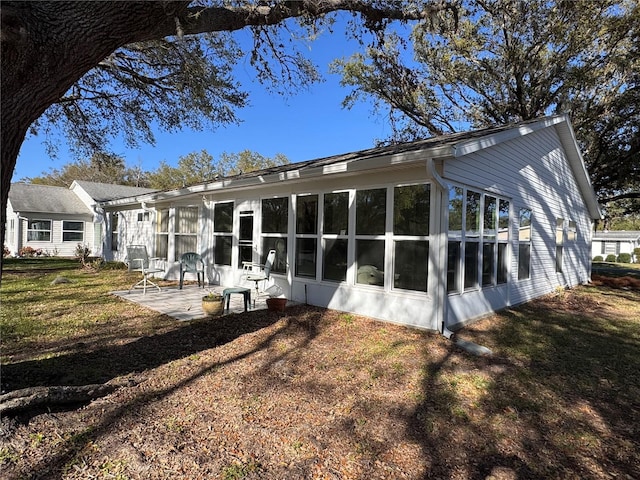 rear view of house with a sunroom, a patio, and a lawn