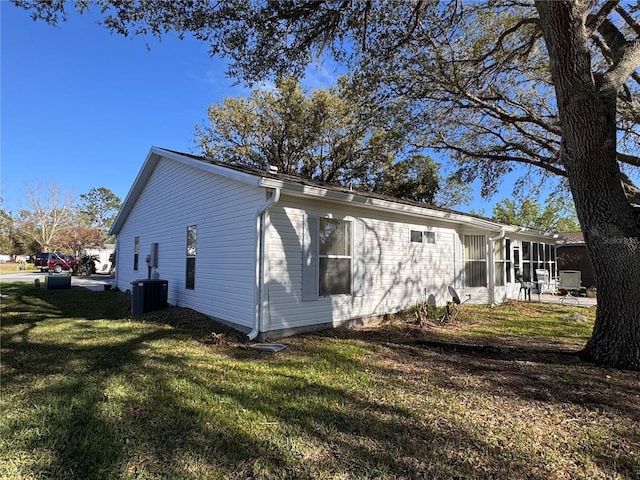 view of side of property with a lawn, cooling unit, and a sunroom