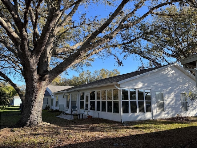 view of home's exterior with a sunroom and a lawn