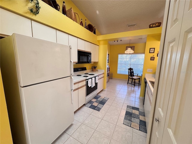 kitchen with light tile patterned floors, a textured ceiling, white appliances, white cabinets, and light countertops