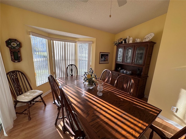 dining room featuring a textured ceiling, wood finished floors, a ceiling fan, and baseboards