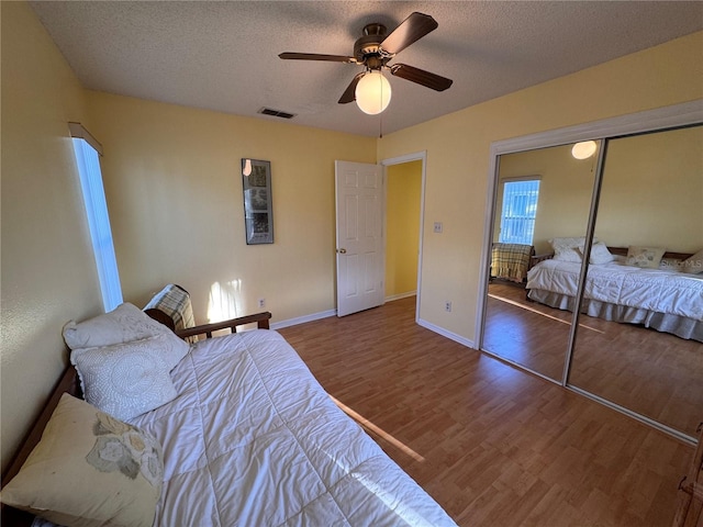 bedroom with ceiling fan, a textured ceiling, baseboards, and wood finished floors