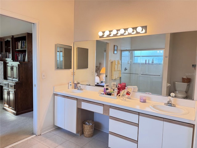 bathroom featuring double vanity, a stall shower, a sink, and tile patterned floors