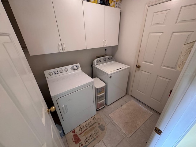 clothes washing area featuring light tile patterned floors, separate washer and dryer, and cabinet space