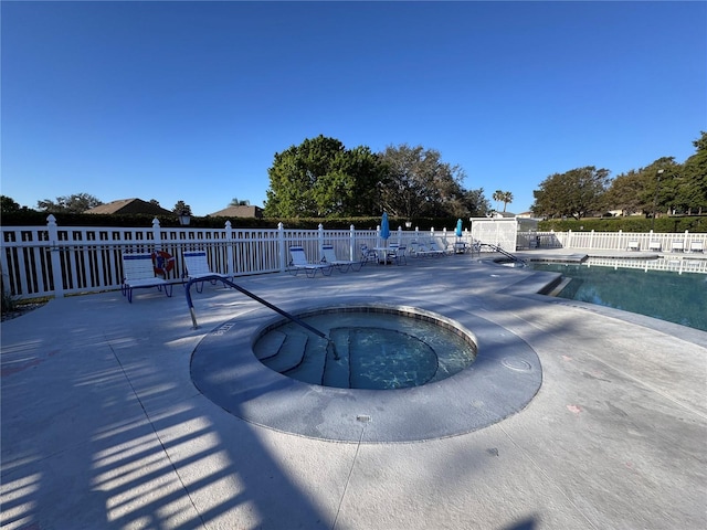 pool with a community hot tub, a patio area, and fence