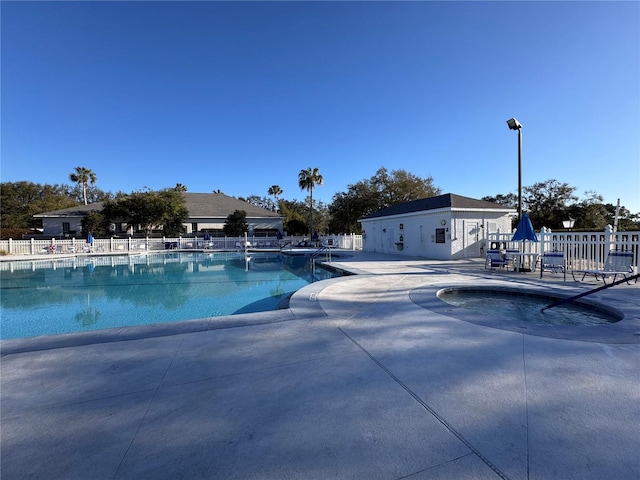 pool featuring an outbuilding, a patio, and fence