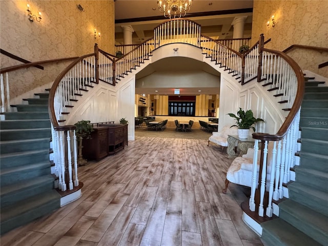 foyer with a towering ceiling, stairway, wood finished floors, and decorative columns