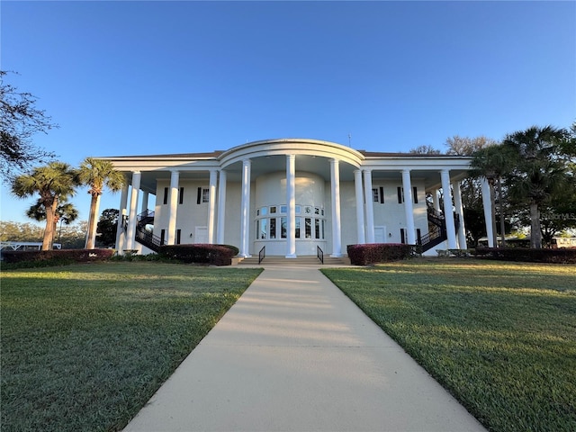 greek revival inspired property featuring a front yard and stucco siding