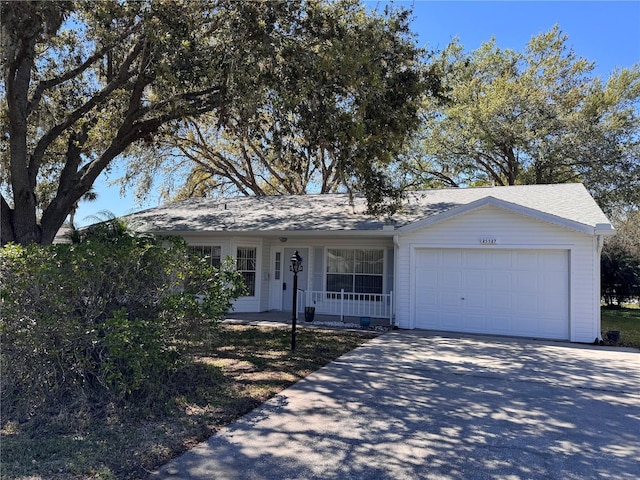 single story home with driveway, a porch, and an attached garage