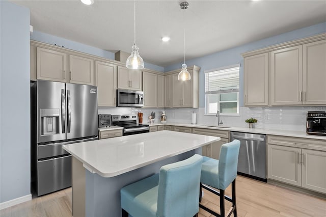 kitchen with decorative backsplash, a kitchen island, appliances with stainless steel finishes, a breakfast bar, and a sink