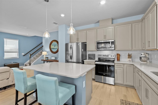 kitchen with tasteful backsplash, visible vents, appliances with stainless steel finishes, light wood-type flooring, and a kitchen breakfast bar