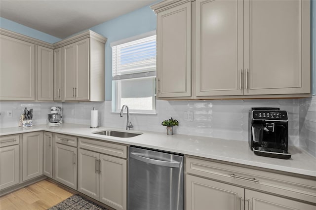 kitchen featuring backsplash, light countertops, light wood-type flooring, stainless steel dishwasher, and a sink