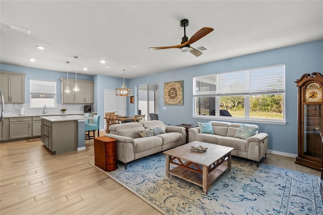 living room with light wood-style floors, a healthy amount of sunlight, visible vents, and a ceiling fan