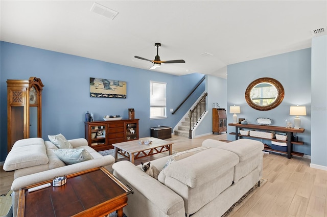 living area with light wood-style floors, visible vents, stairway, and ceiling fan