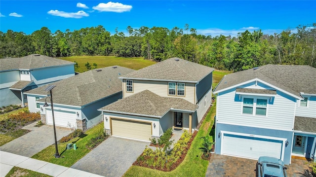 traditional-style home with a shingled roof, decorative driveway, and stucco siding