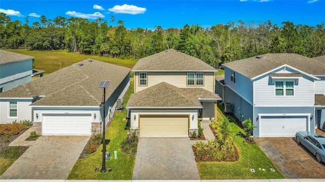 traditional home featuring roof with shingles, decorative driveway, and stucco siding