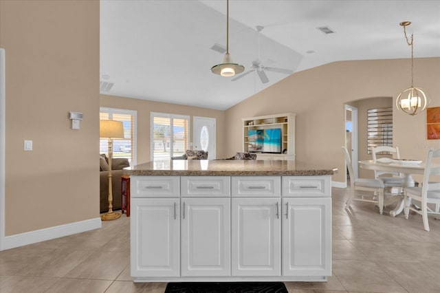 kitchen featuring arched walkways, lofted ceiling, a kitchen island, hanging light fixtures, and white cabinetry