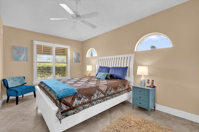 bedroom with a textured ceiling, ceiling fan, multiple windows, and baseboards