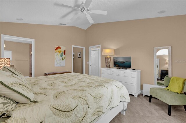 bedroom with light tile patterned floors, visible vents, a ceiling fan, vaulted ceiling, and ensuite bath