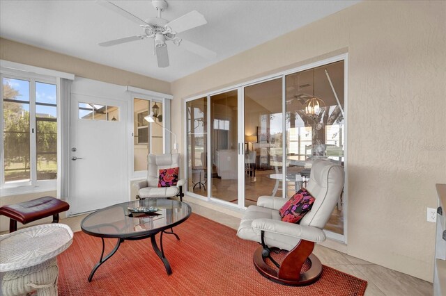 sunroom / solarium featuring ceiling fan with notable chandelier