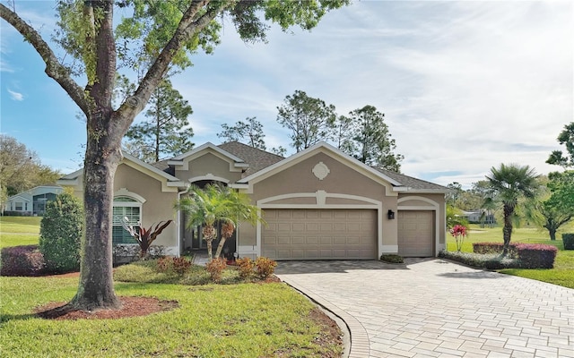 view of front facade featuring a garage, a front lawn, decorative driveway, and stucco siding