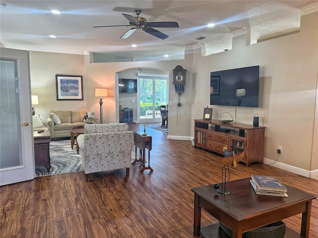 living area with arched walkways, wood finished floors, a ceiling fan, baseboards, and crown molding