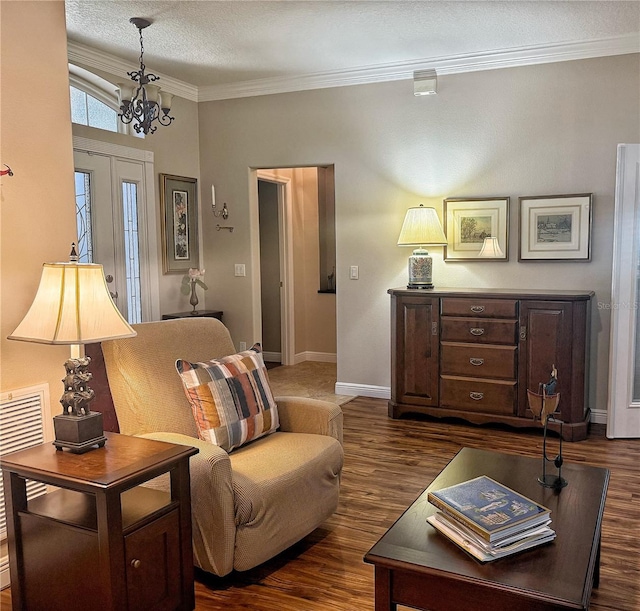 interior space featuring a textured ceiling, a notable chandelier, baseboards, ornamental molding, and dark wood finished floors