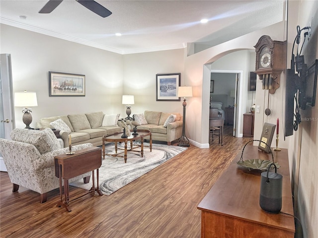 living room featuring arched walkways, ornamental molding, wood finished floors, and a ceiling fan