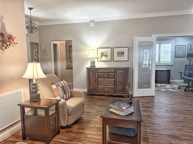 living area featuring a notable chandelier, a textured ceiling, ornamental molding, and dark wood-style flooring